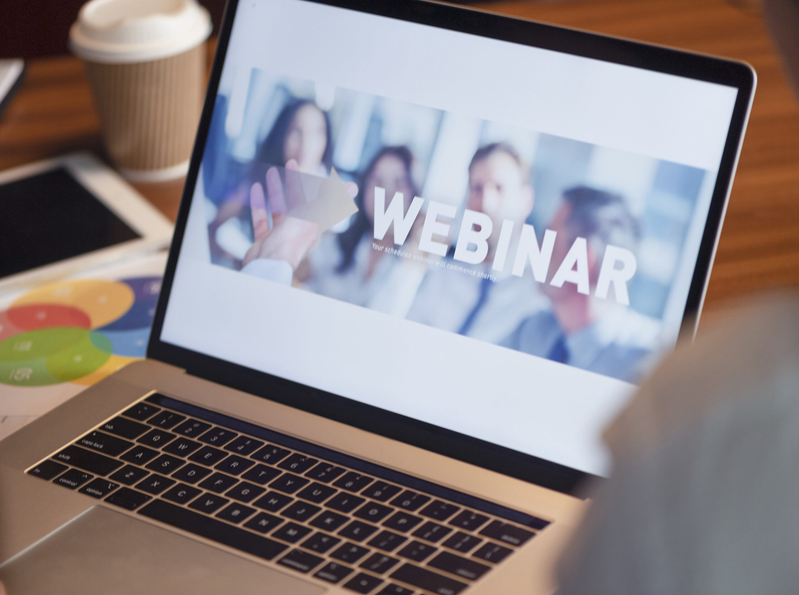 Businessman looking at a webinar screen on a computer. There is a image of a group of people learning on the screen