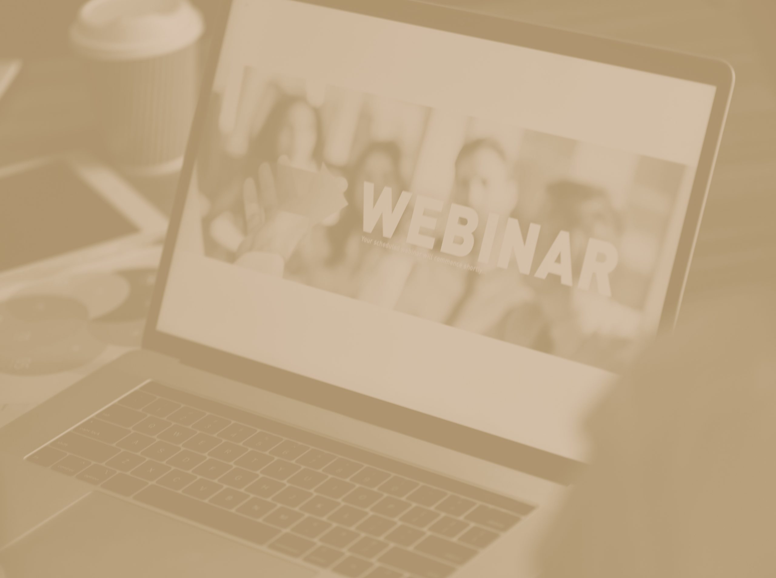 Businessman looking at a webinar screen on a computer. There is a image of a group of people learning on the screen